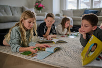 Children reading books on a rug in a living room